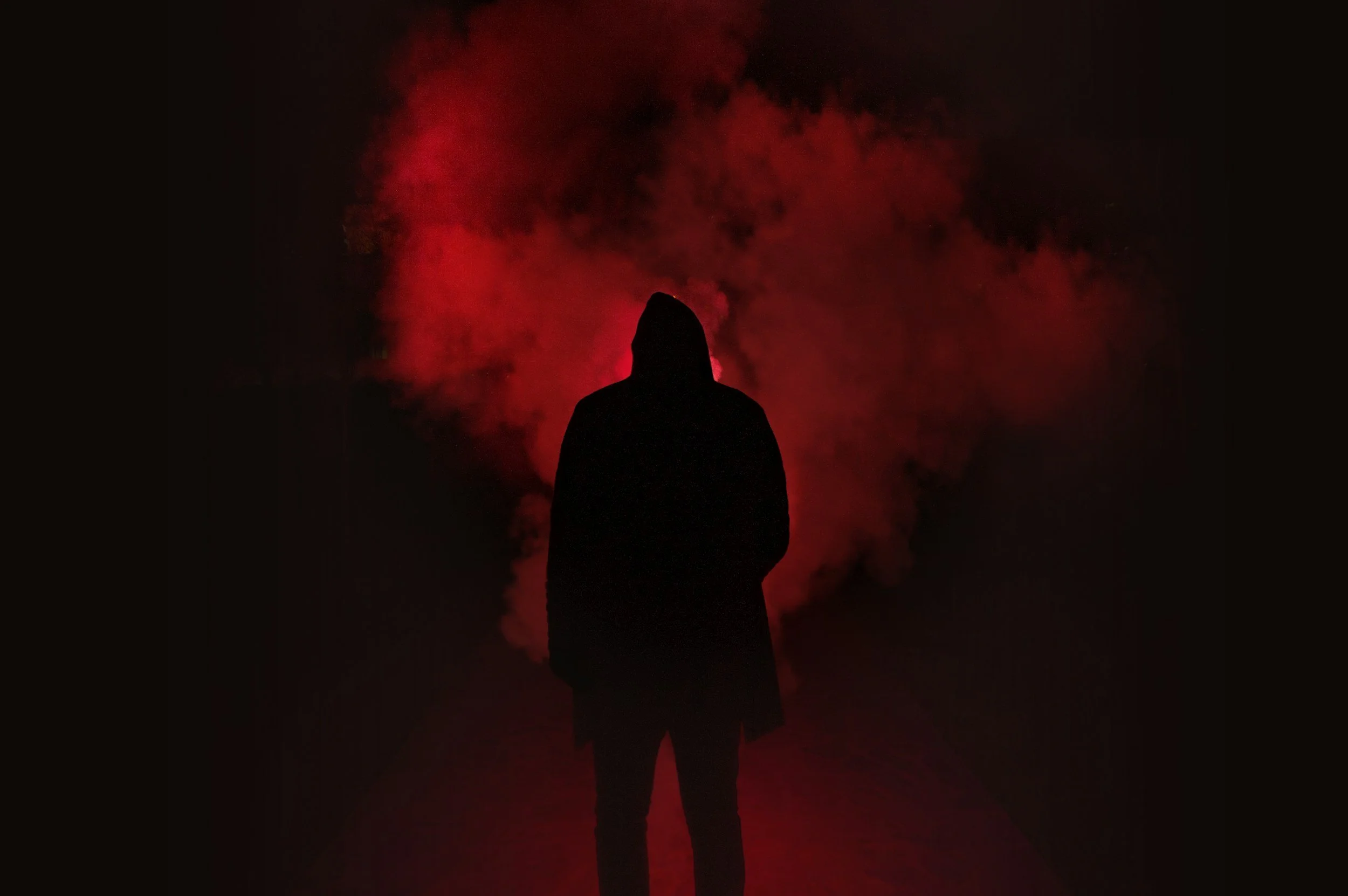 Silhouetted figure standing in red smoke