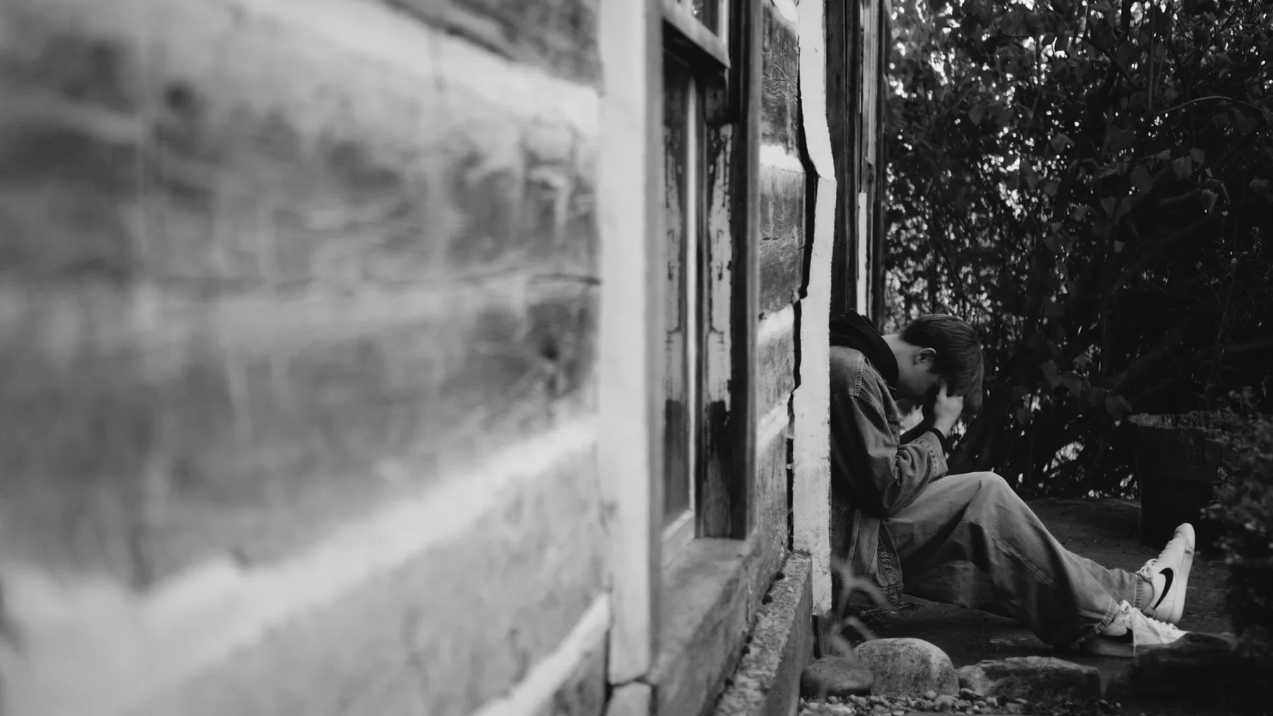 Man seated beneath a window in a black-and-white Colorado scene