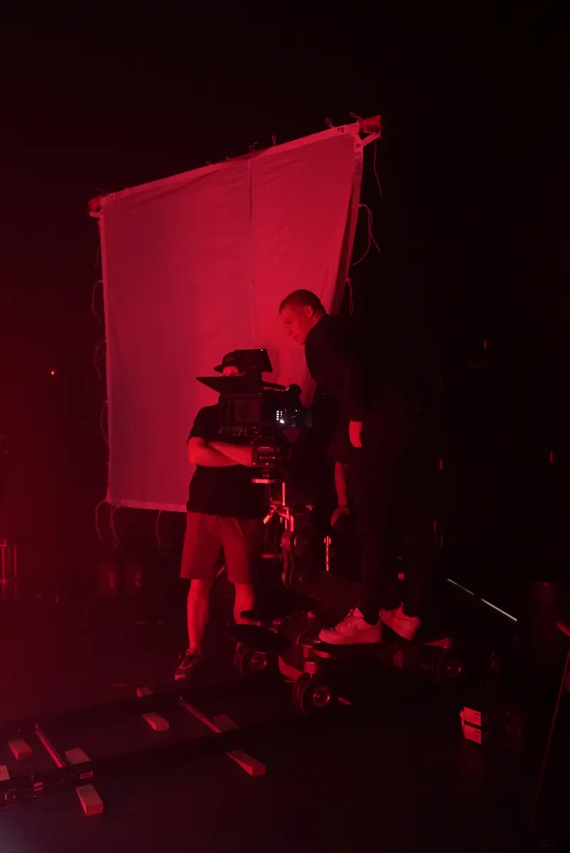 Camera and crew silhouetted in red light on The Keepers set