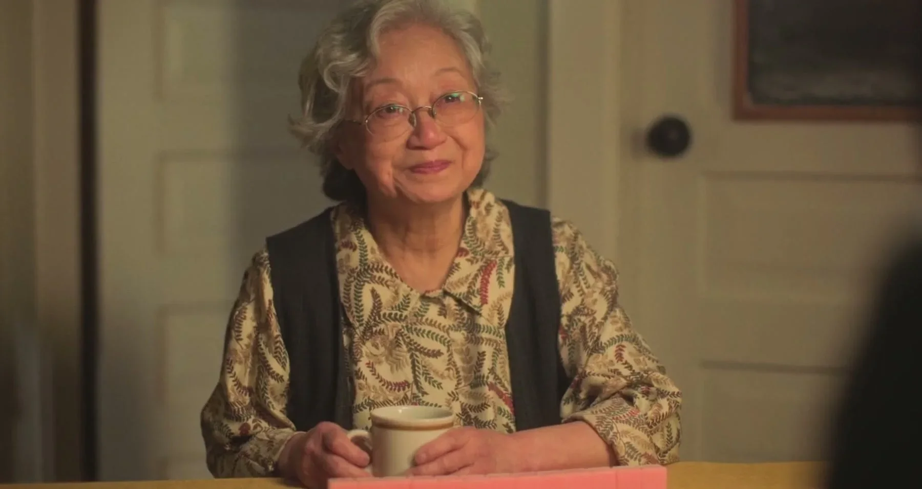Finished-film frame of the elder character seated at a table in The Knitting Diaries.