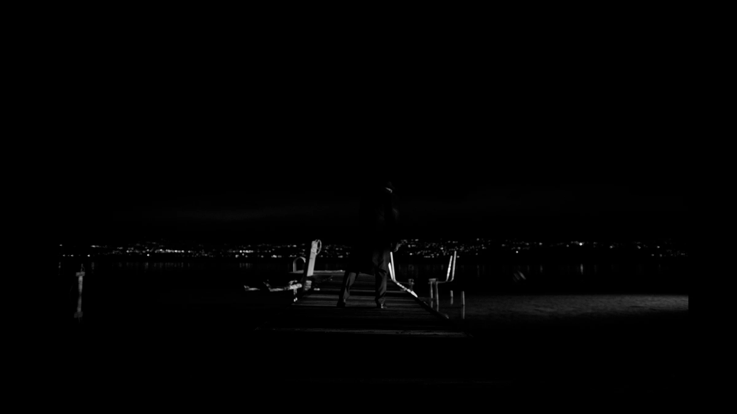 A silhouetted figure on a dock in a black-and-white Last of a Dying Breed frame