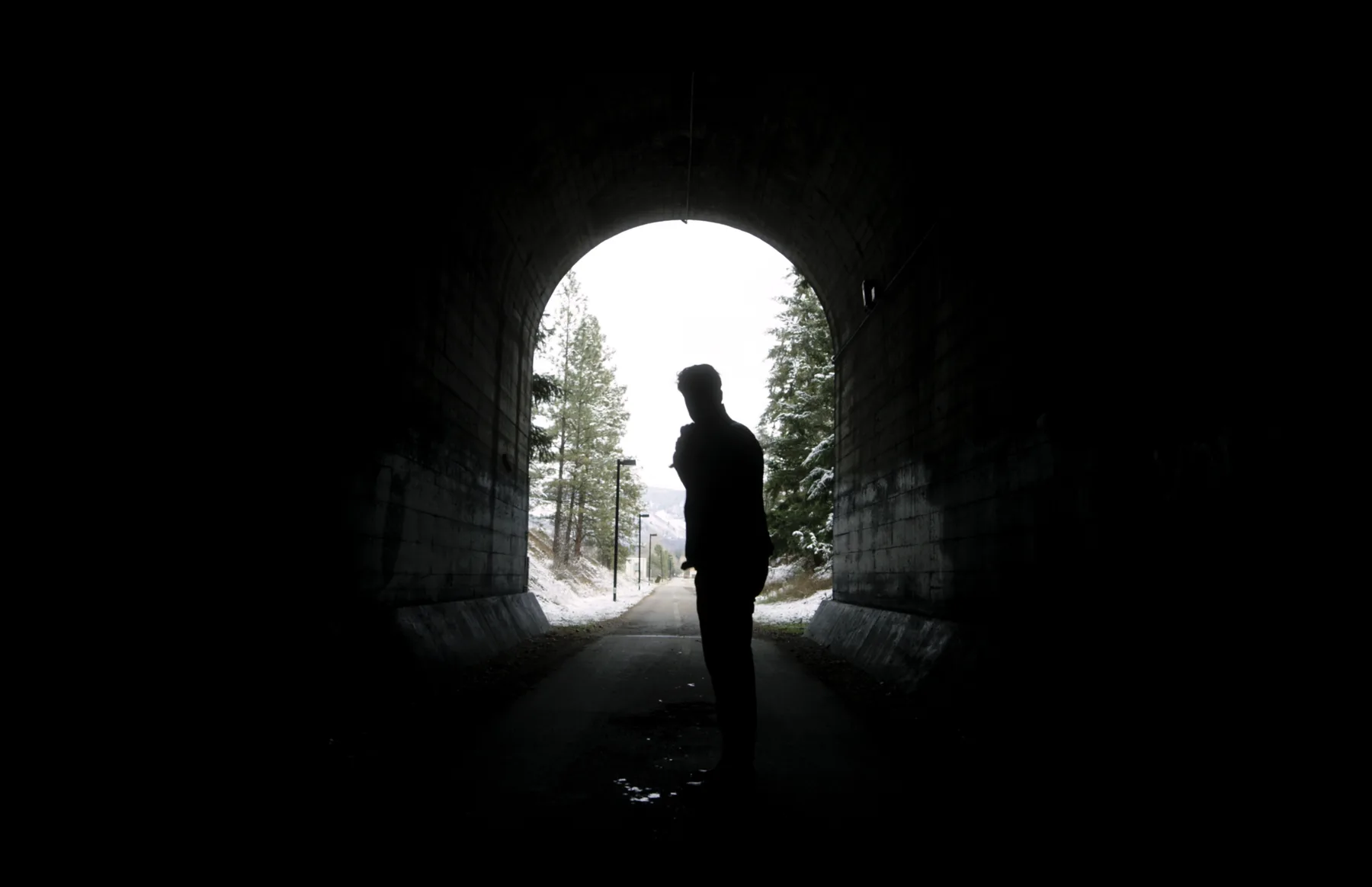 Silhouetted actor standing at the mouth of a railway tunnel
