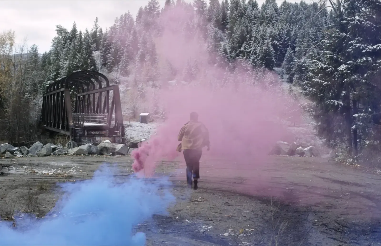 Actor moving through coloured smoke beside a Princeton bridge