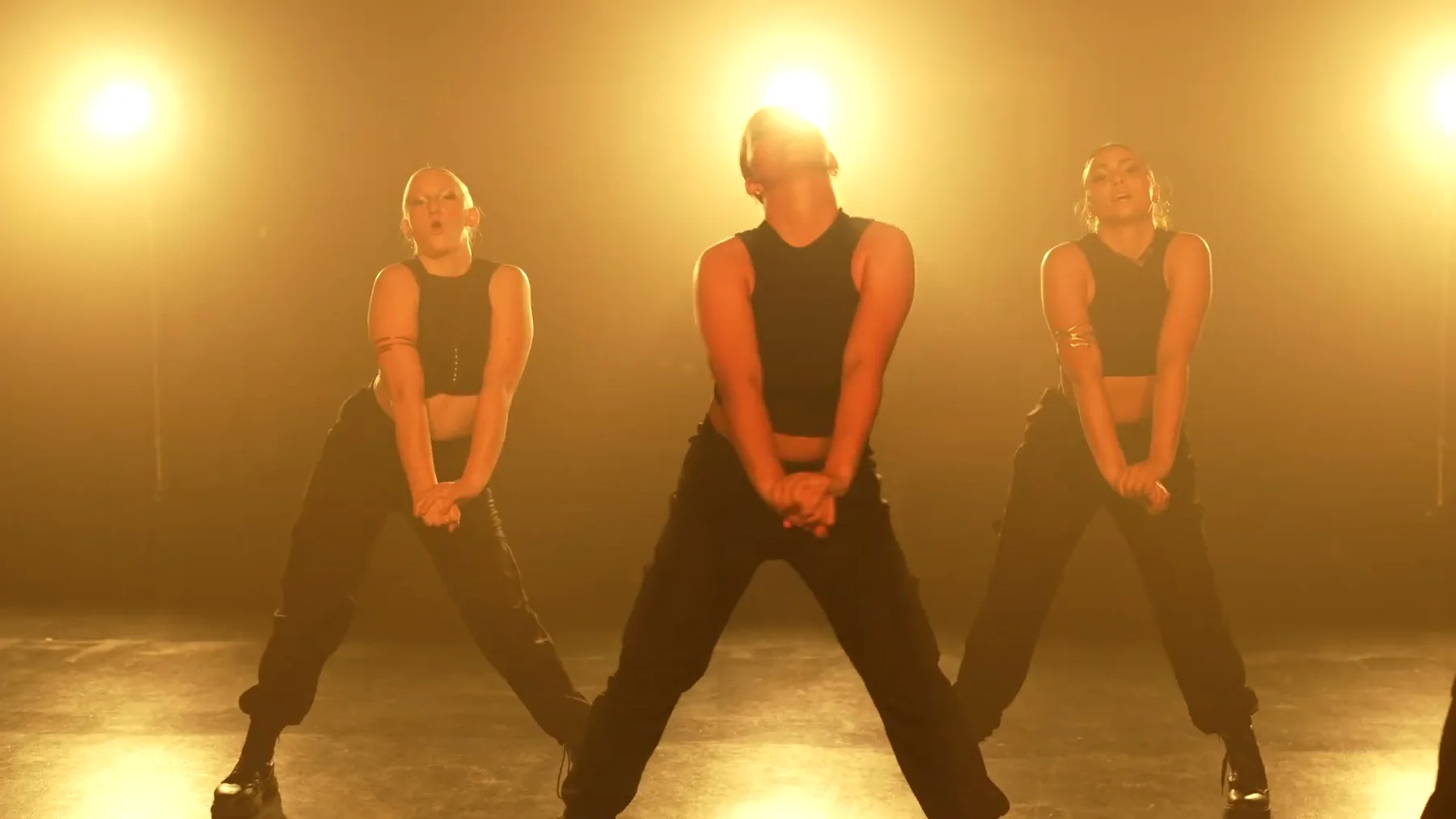Three Sockeye dancers standing in amber backlight in the 2023 film
