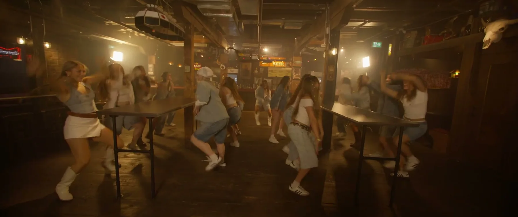 Sockeye dancers moving through a warm bar interior in the 2025 film
