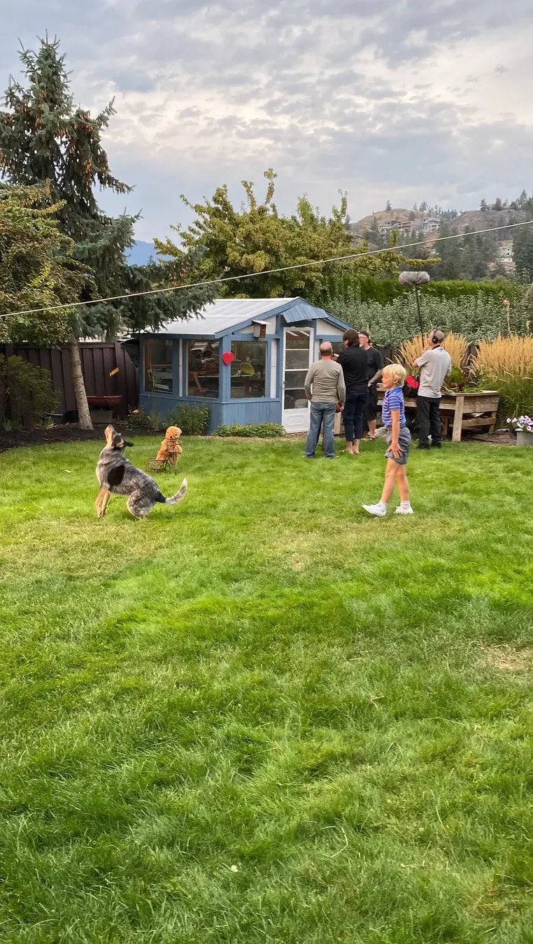 Three Hearts yard scene with young actors, family members and dogs gathered near the garden